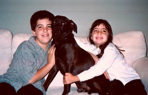 Jazz sitting on a sofa between a boy and a girl, who are both hugging her and smiling.